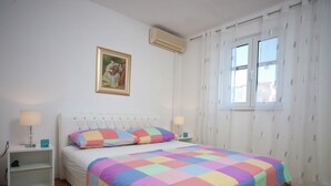 A bedroom with a bed, two bedside tables, a window, and a wall-mounted air conditioner. - Holiday Home in Okrug Gornji Near the Sea (Okrug)