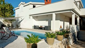 A modern house with a swimming pool, outdoor seating, and potted plants. - Holiday Home in Okrug Gornji Near the Sea (Okrug)