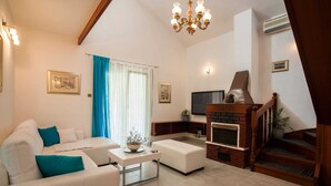 A living room with a sofa, a coffee table, a fireplace, a TV, and a staircase. - Holiday Home in Okrug Gornji Near the Sea (Okrug)