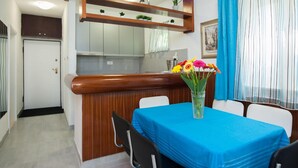 A dining area with a blue tablecloth, a vase of flowers, and a wooden counter with a mirror above it. - Holiday Home in Okrug Gornji Near the Sea (Okrug)
