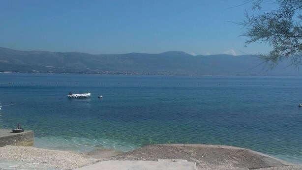 A clear view of a calm lake with a boat in the distance, surrounded by mountains and a clear sky. - Apartment 5 km From Trogir's Center (Split)