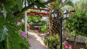 A garden patio with a pergola, stone lanterns, and flowering plants. - Apartment 5 km From Trogir's Center (Split)