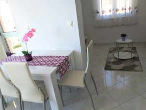A dining area with a table, chairs, a potted orchid, and a small round table with a vase.