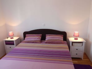 A bedroom with a bed, two bedside tables, and two lamps.