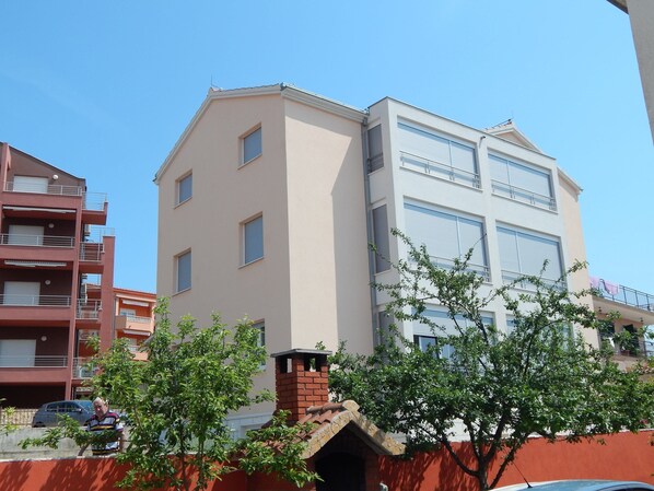 A multi-story residential building with a beige facade, multiple windows, and balconies.