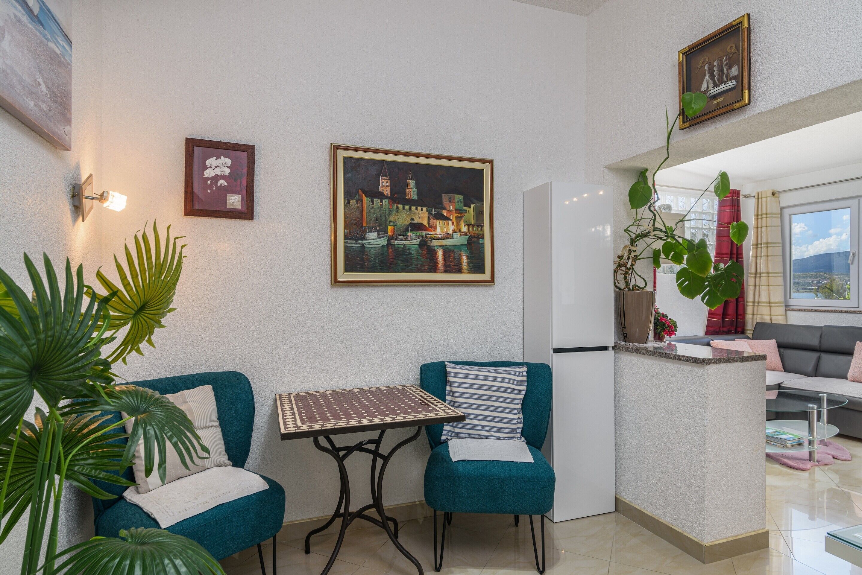 A modern living room with teal chairs, a small table, and a painting of a cityscape.