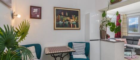 Ein modernes Wohnzimmer mit Türkis-Sesseln, einem kleinen Tisch und einem Stadtbild.