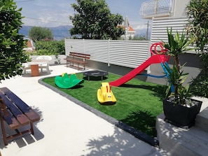 A children's play area with a slide, a green and yellow ride-on toy, and a trampoline.