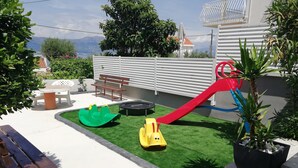 A children's play area with a slide, a green and yellow ride-on toy, and a trampoline.