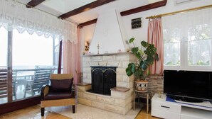 Un salon avec une cheminée, un téléviseur et une grande fenêtre.