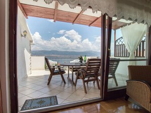 A balcony with a table and chairs, a view of the sea and mountains, and a lace-covered ceiling. - Top Floor Apartment With a Sea View Terrace Near the Sea (Split)