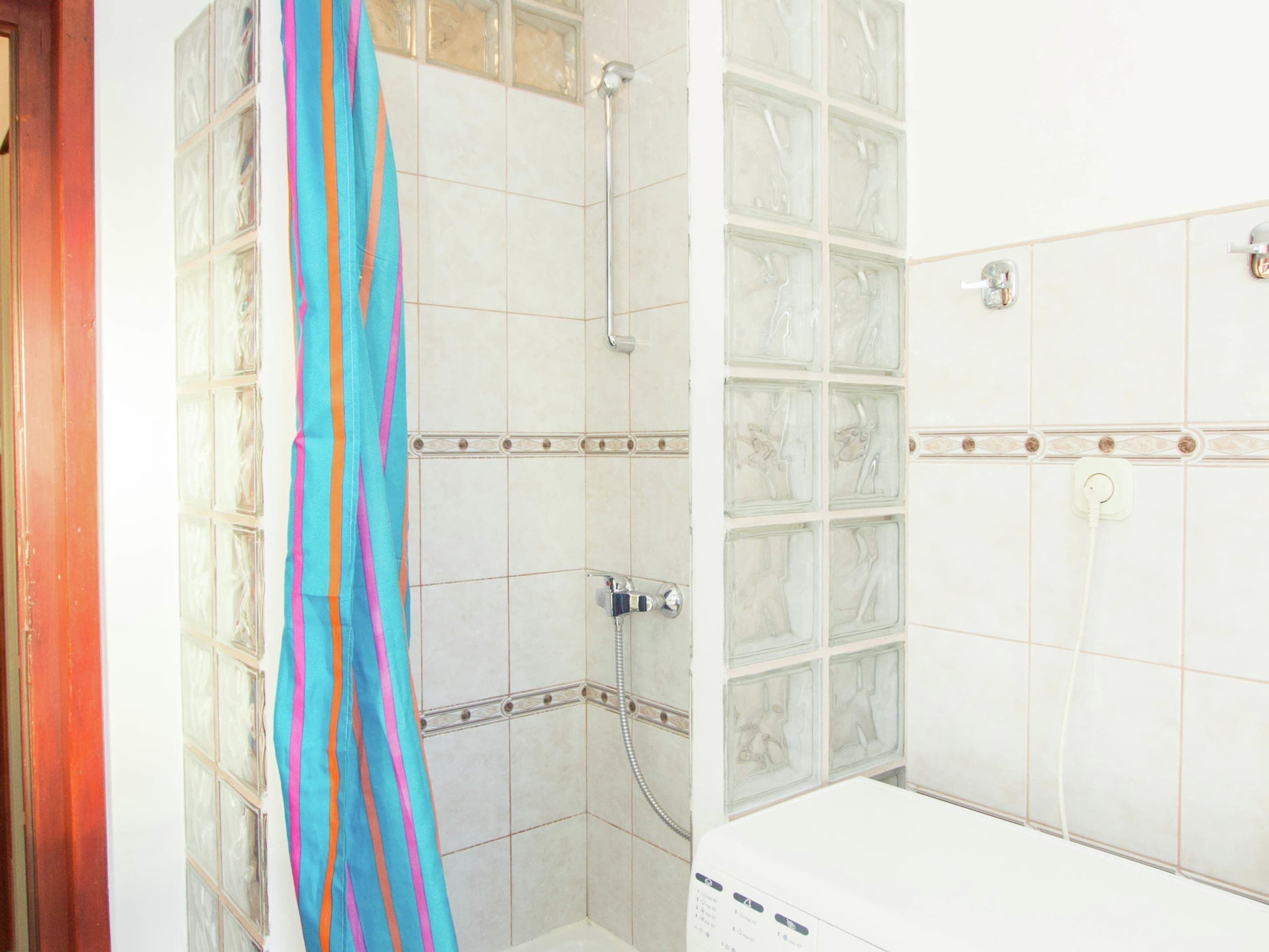 Un bagno con doccia, un divisorio in vetro e un lavandino bianco.