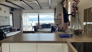 Une cuisine moderne avec vue sur la mer, un coin repas avec un canapé et un salon doté d’une cheminée.