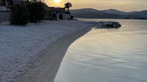 Une plage avec une maison et des montagnes en arrière-plan.