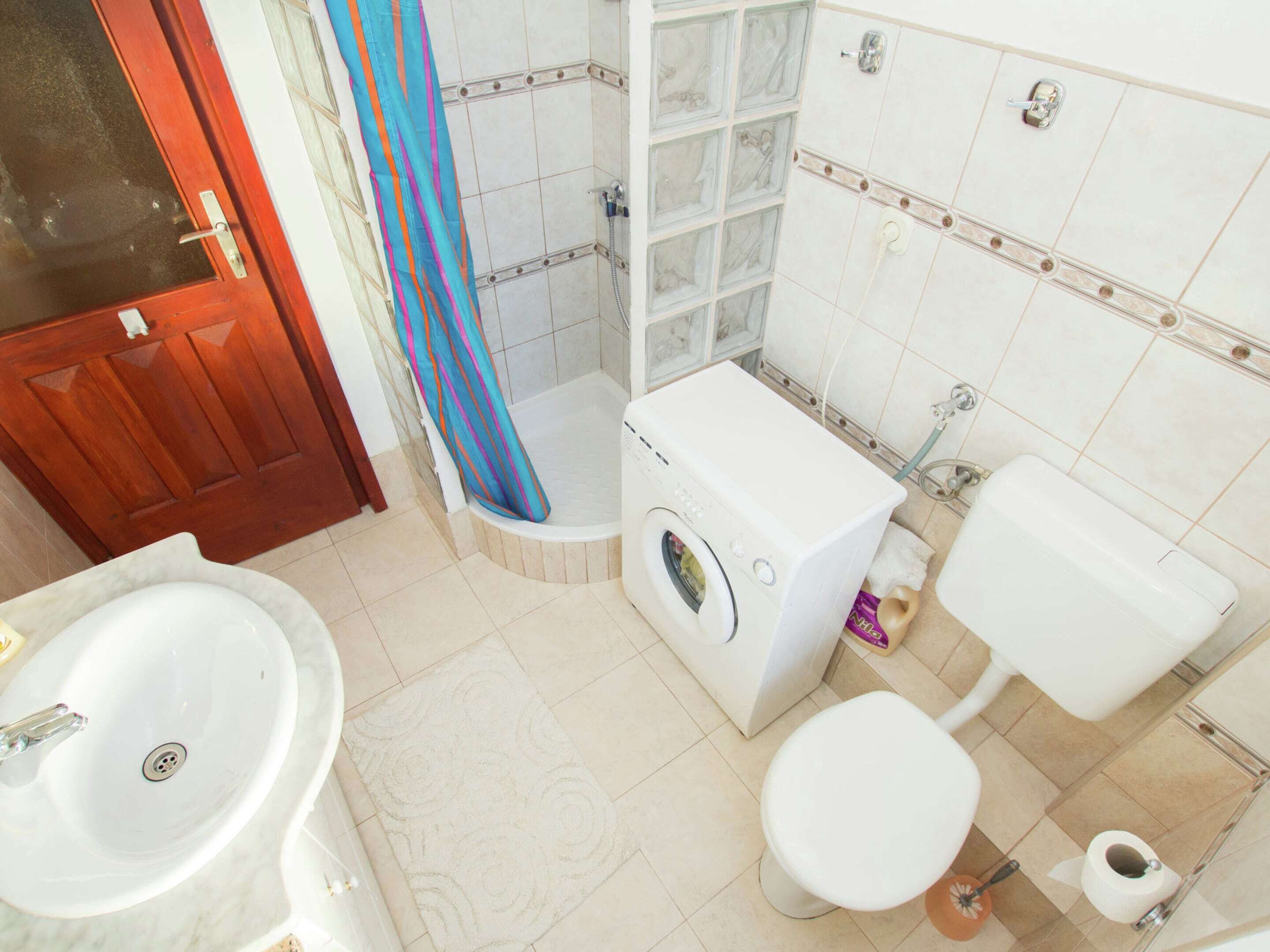 A compact bathroom with a sink, toilet, and washing machine.