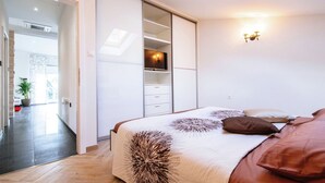 Une chambre à coucher avec un lit, une armoire, un téléviseur et une fenêtre de toit.