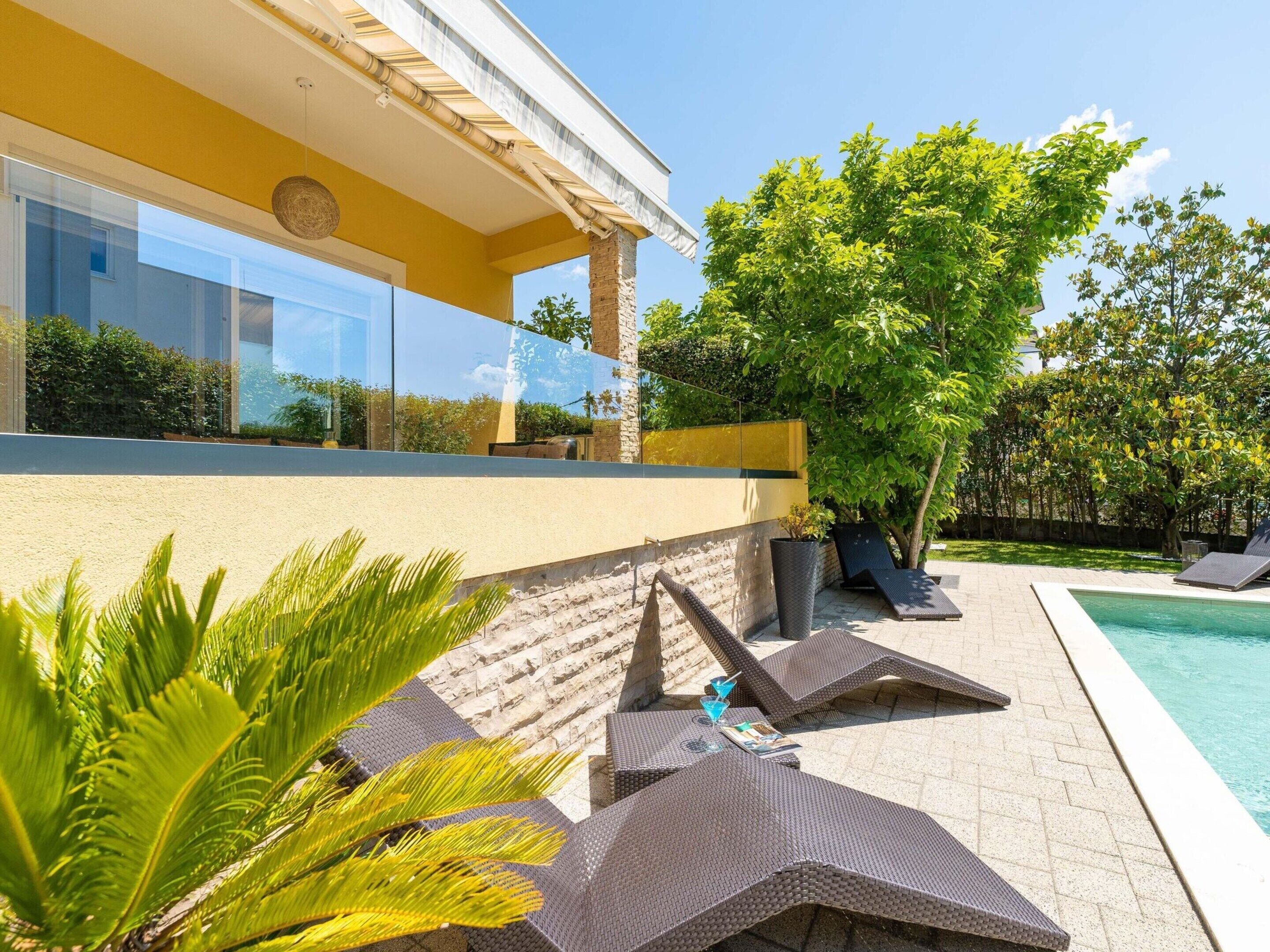 A modern outdoor pool area with lounge chairs and a stone wall.