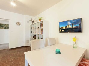 Relax in a stylish living room with a comfortable sofa, dining table, and flat-screen TV.