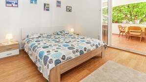 A bedroom with a bed, bedside tables, a nightstand, and a view of an outdoor patio with a table and chairs.