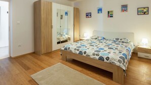 A bedroom with a bed, a wardrobe, a mirror, and a nightstand.