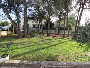 Enjoy the serene outdoor space with a lush lawn, trees, and a garden, surrounded by a charming building with a balcony.