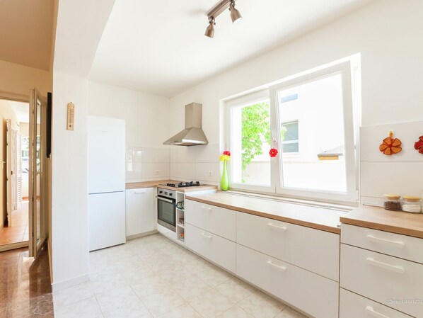 Enjoy cooking in this well-equipped kitchen with a stove, oven, and window overlooking lush greenery.