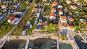 An aerial view of a coastal residential area with houses, a marina, and clear waters.