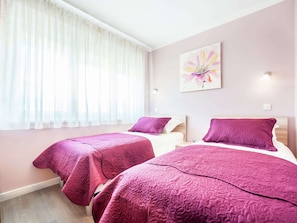 A hotel room with two beds, each with a purple bedspread, a white headboard, and a window with sheer curtains. - Modern Newly Built Apartment, Geat Location, Private Parking Space, WiFi (Zadar)