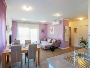 A modern living room with a sofa, chairs, a dining table, and a kitchen area with a sink. - Modern Newly Built Apartment, Geat Location, Private Parking Space, WiFi (Zadar)