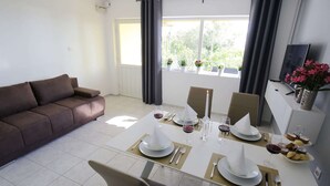A modern living room with a dining area, a sofa, a TV, and a window with curtains.