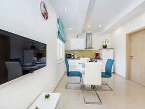 Enjoy a clean and functional space with a dining area, kitchen, and living room featuring a flat-screen TV.