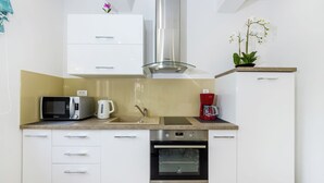 A modern kitchen with white cabinets, a stainless steel range hood, a microwave, a coffee maker, and an oven. - Luxury Apartment in Zadar With Covered Terrace (Zadar)