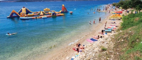 A beach with inflatable structures and people sunbathing.