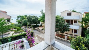A residential building with a balcony, a view of the street, and surrounding greenery. - Comfortable Apartment With Balcony in a Quiet Area, Near the Beach (Zadar)