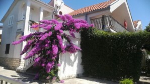 A building with a white facade, a red-tiled roof, and a satellite dish. - Comfortable Apartment With Balcony in a Quiet Area, Near the Beach (Zadar)