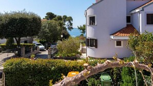 A coastal residential area with white buildings, a paved street, and a clear view of the sea. - Comfortable Apartment With Balcony in a Quiet Area, Near the Beach (Zadar)