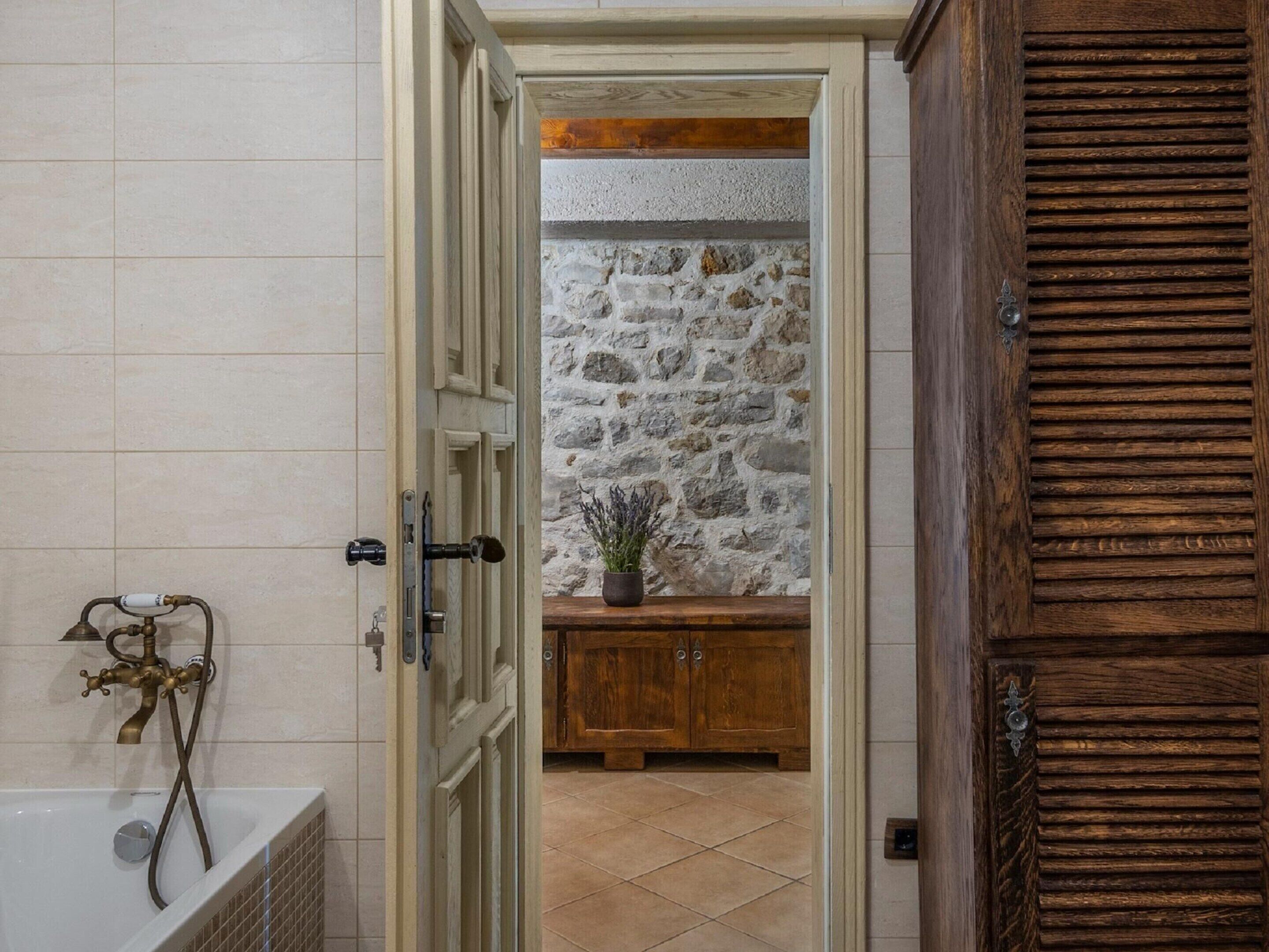 Een badkamer met een bad, een stenen muur en houten kastjes.