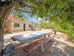A stone building with a tiled roof, a picnic table, and benches. - Holiday Home in Seline Near the Sea (Starigrad)