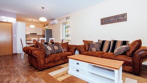 A living room with a brown leather sofa set, a white coffee table, and a dining area in the background. - Spacious Holiday Home in Pakoštane near Sea (Pakostane)