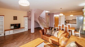 A modern living room with a wooden floor, a brown leather sofa, a TV, and a staircase leading to another level. - Spacious Holiday Home in Pakoštane near Sea (Pakostane)