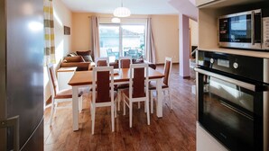A modern kitchen with a built-in microwave and oven, a dining area with a wooden table and chairs, and a large window offering a view of the outdoors. - Spacious Holiday Home in Pakoštane near Sea (Pakostane)