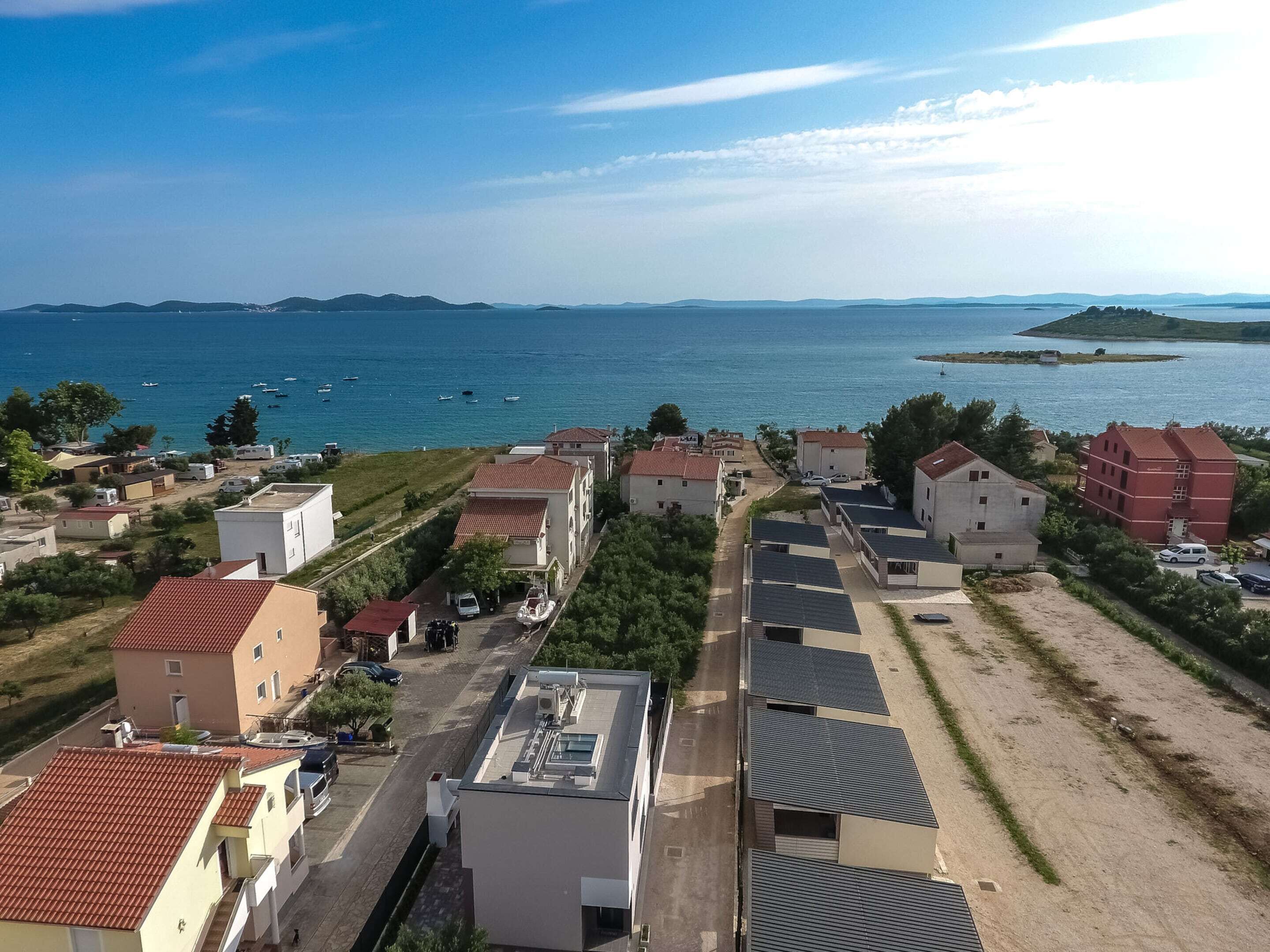 A coastal residential area with houses, a road, and boats on the water.