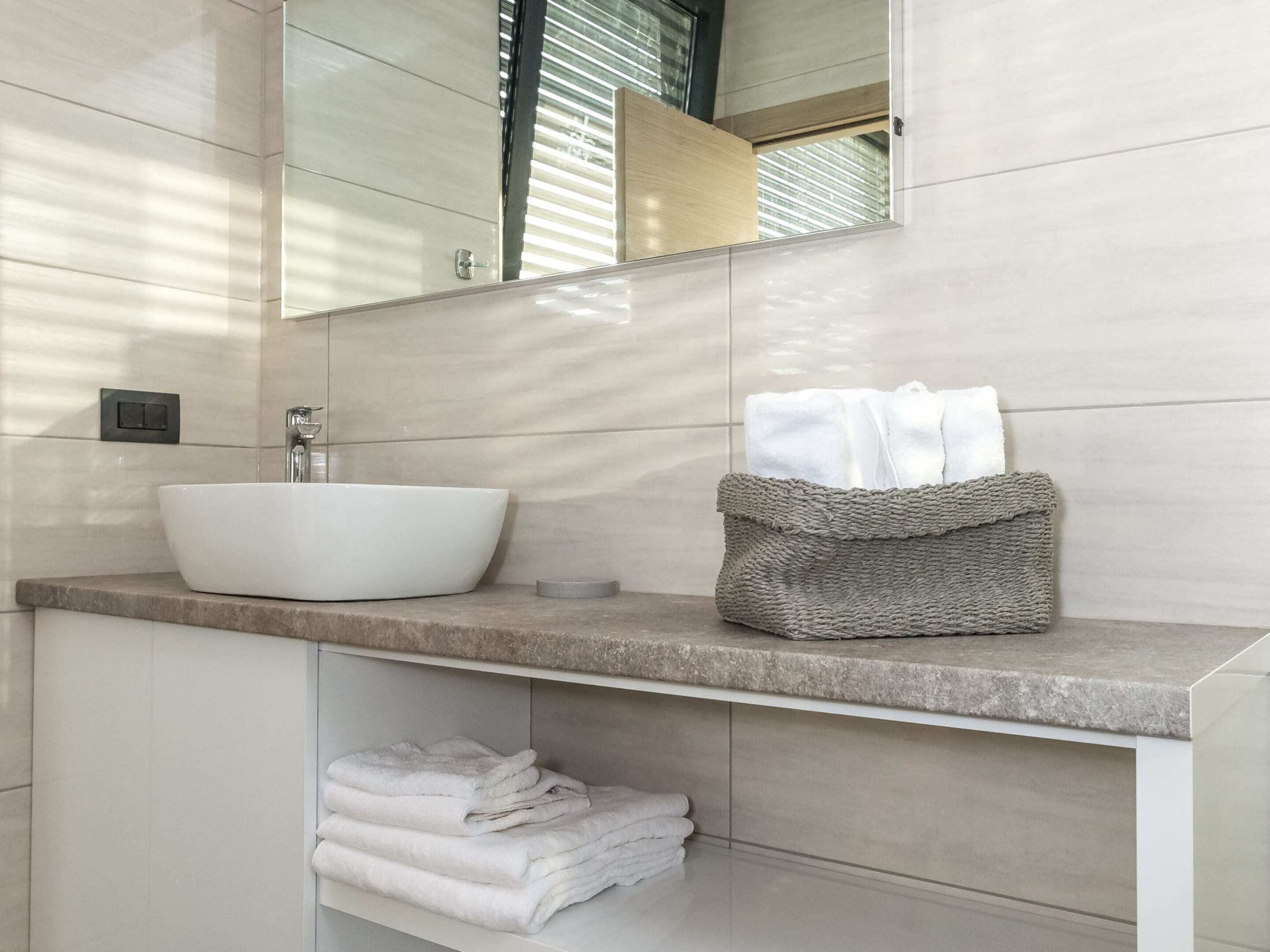 A modern bathroom with a large white sink, a mirror, and a towel rack.