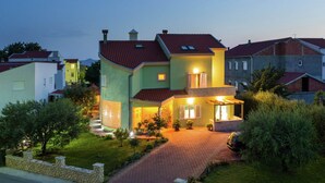 A two-story house with a red-tiled roof, a stone pathway leading to the entrance, and a well-maintained lawn. - New Luxury Apartment With Nice Garden and Barbecue in a Quiet Area, Wifi (Zadar)