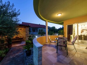 Eine Außenpatio mit einer gebogenen Steinmauer, einem Tisch mit Stühlen und Topfpflanzen.
