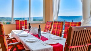 Un coin repas avec une table dressée pour quatre personnes, de grandes fenêtres offrant une vue panoramique et des chaises à motifs écossais.