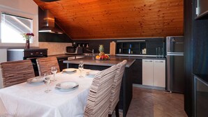 Uma cozinha moderna com teto de madeira, uma área de jantar com cadeiras listradas e um forno embutido.