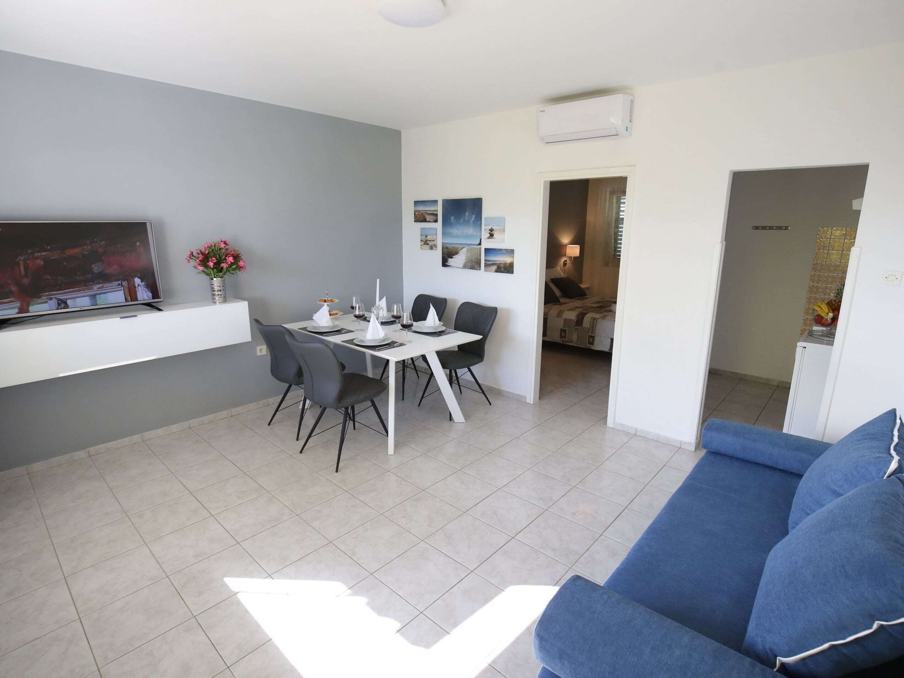 A modern living room with a dining area, a sofa, and a TV.