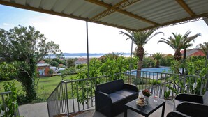 A covered outdoor seating area with a view of a pool and greenery. - Modern Holiday Home With Pool (Bibinje)