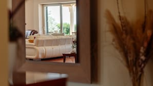 Un salon moderne avec un canapé blanc, une table basse et une grande fenêtre offrant une vue sur l’extérieur.